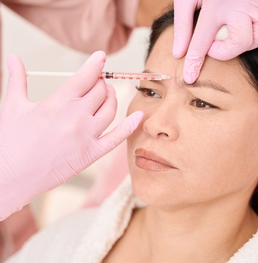 Effective injection rejuvenation procedure in a cosmetology salon, a specialist works in pink protective gloves