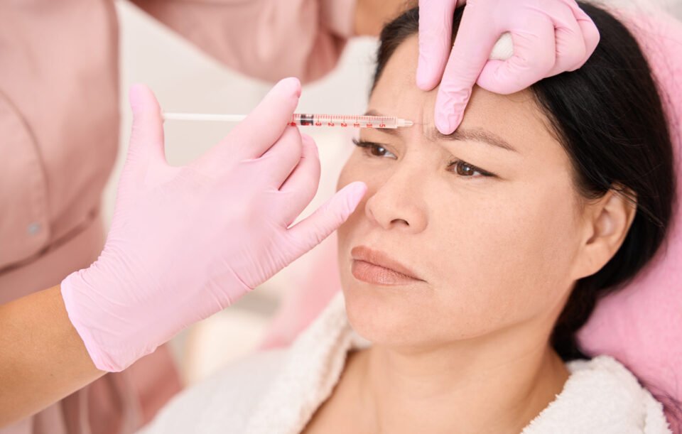 Effective injection rejuvenation procedure in a cosmetology salon, a specialist works in pink protective gloves